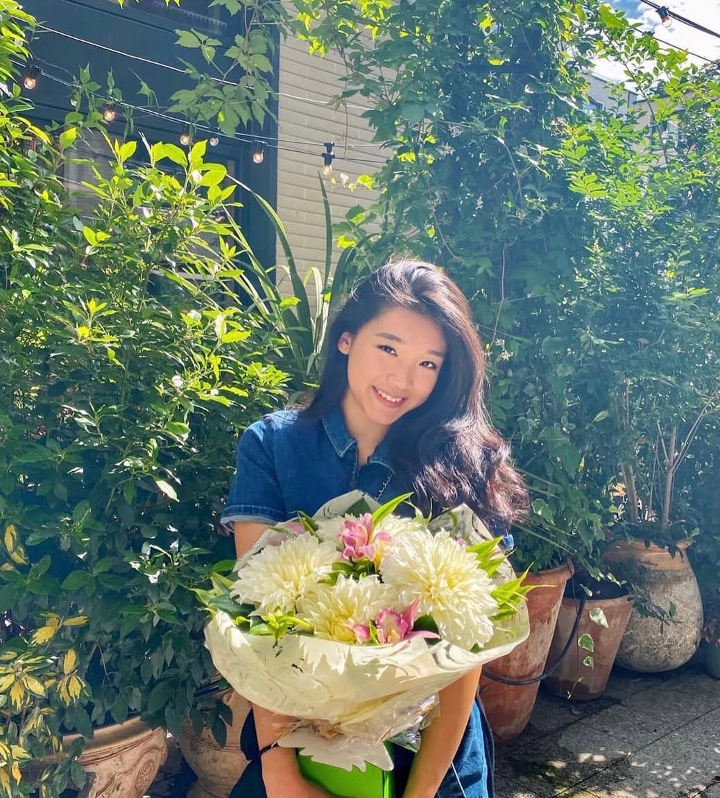 Canna Yuan holding a bouquet in a garden